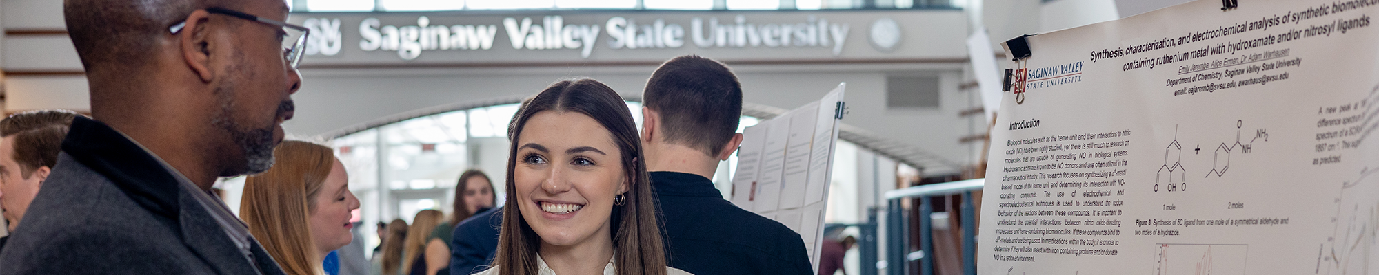A student being mentored by a professor while giving a presentation